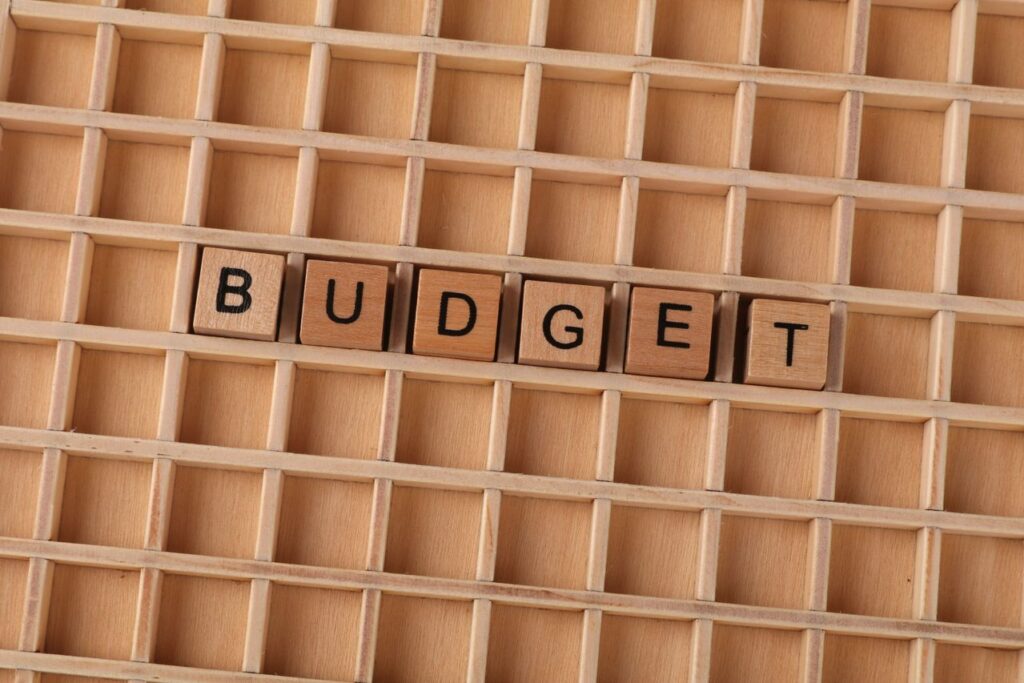 Tiles spelling BUDGET on a wooden grid, conveying financial planning ideas.