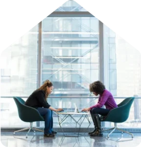 business-protection-insurance-2webp - Kierten Kooner Two colleagues collaborate at a glass coffee table with laptops in a bright office environment.